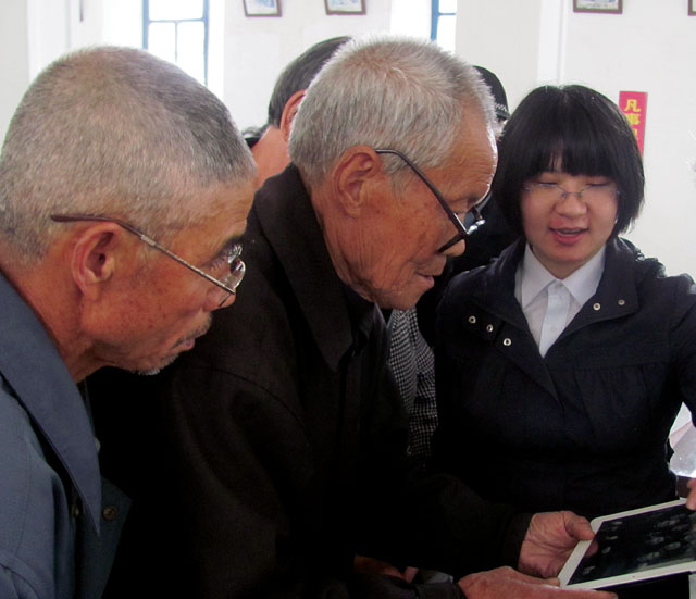 In the village of Bihu, elders look at historical photos on Fr. Mike’s iPad, recognizing some of the Scarboro priests and Grey Sisters they knew as children.
